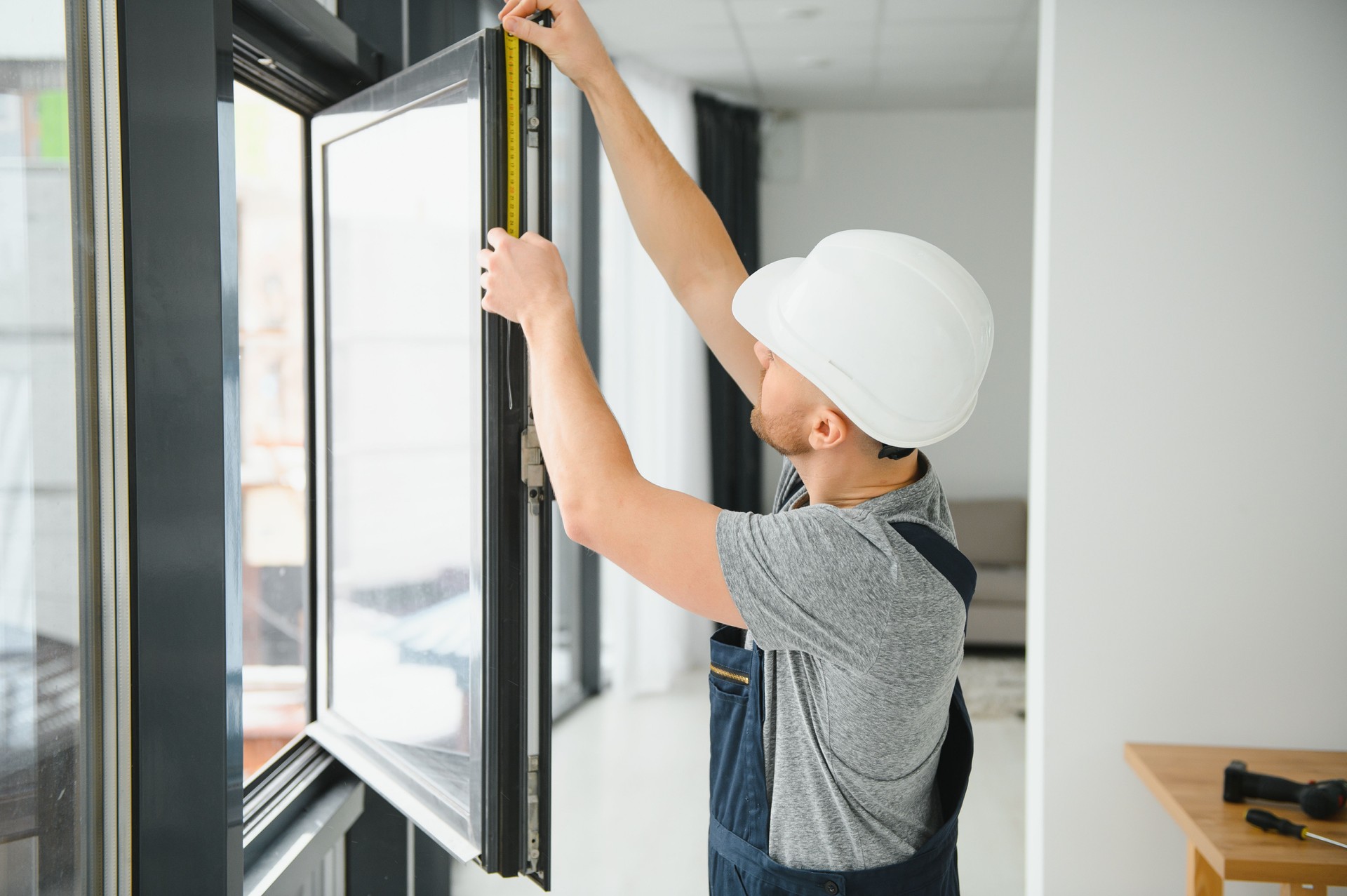 handsome young man installing bay window in new house construction site